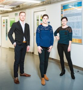 Three members of the Cahová group in 2016, standing in an institute corridor beside a scientific poster
