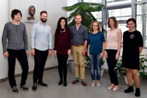 Seven members of the Cahová group in 2017, standing in a room with a palm and a bust