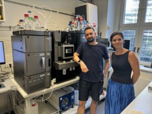 Two group members standing beside the newly installed Acquity Premium System with Xevo TQ mass spectrometer