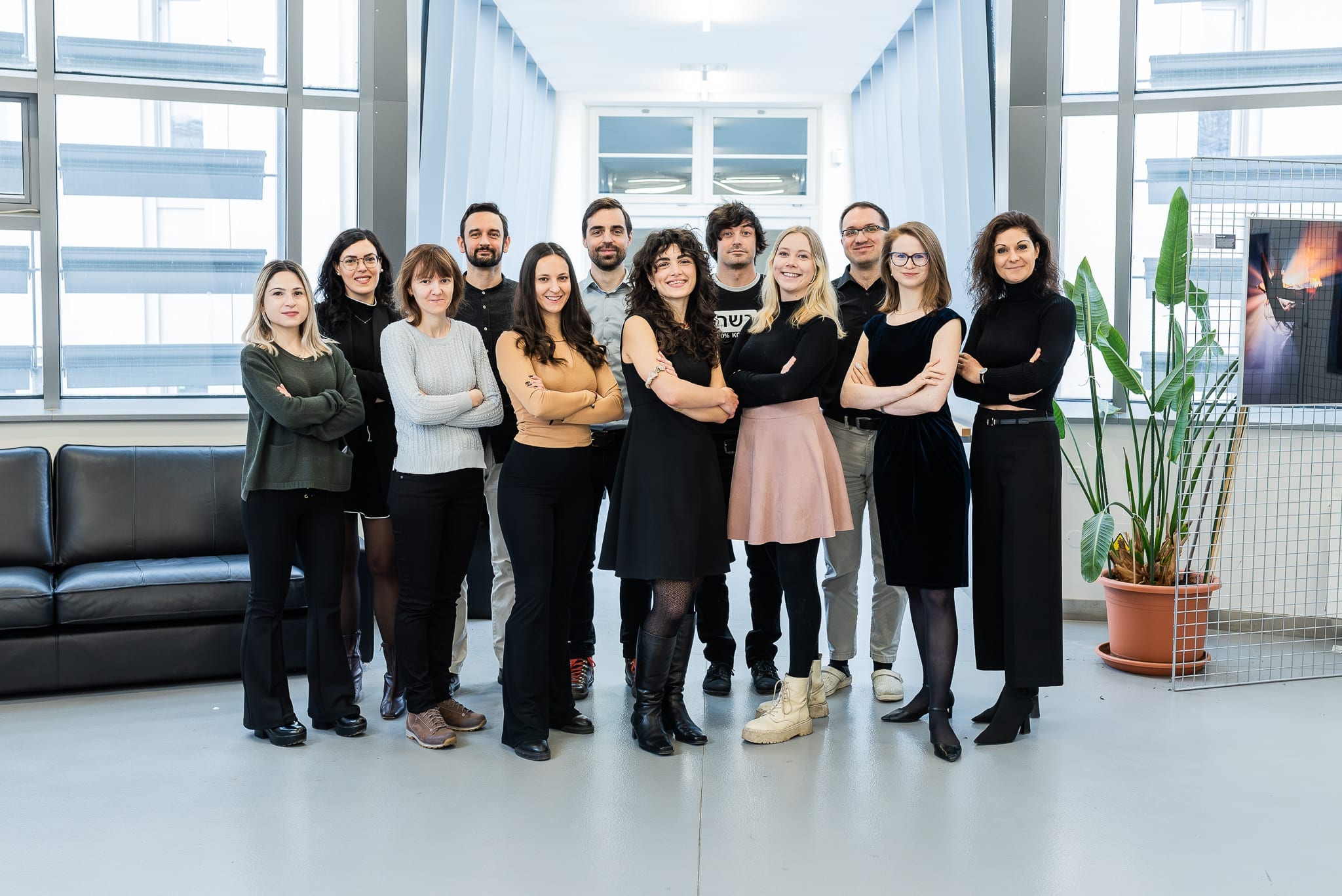 The Cahová group in 2025, fourteen members standing together in a bright, window-lined room